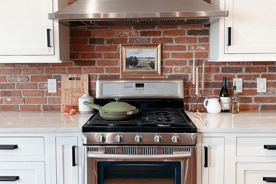 brick backsplah in white cabinet kitchen